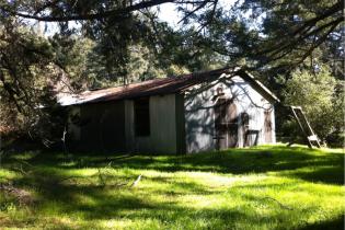 A brown house, a field a grass in front.