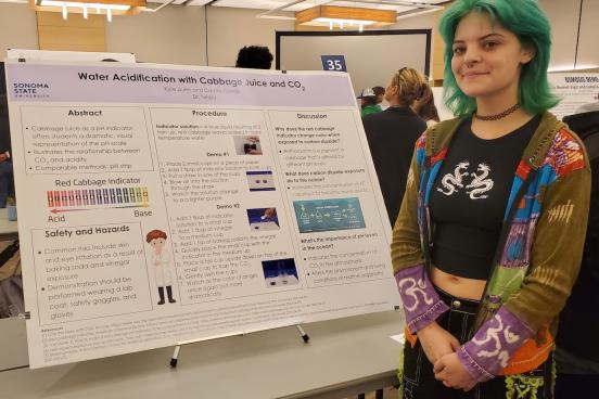 student stands next to her poster