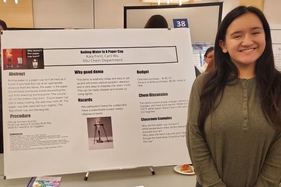 student standing next to poster