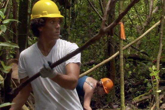 man in hard hat holds log in forest
