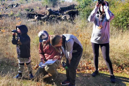 Los niños miran un libro y a través de binoculares