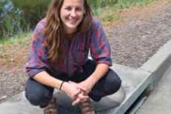 Student squatting over sewer drain