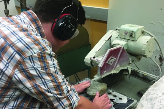Student making a thin section from a sample of rock