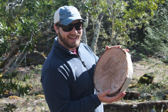 Student holding cross section of a tree trunk