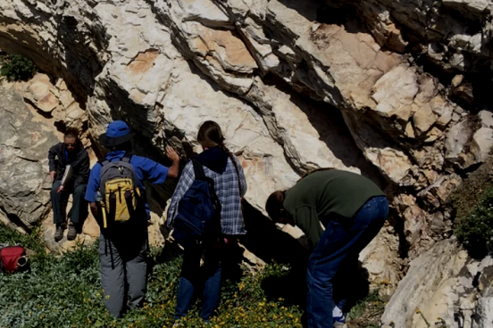 students in front of a rocky wall outside