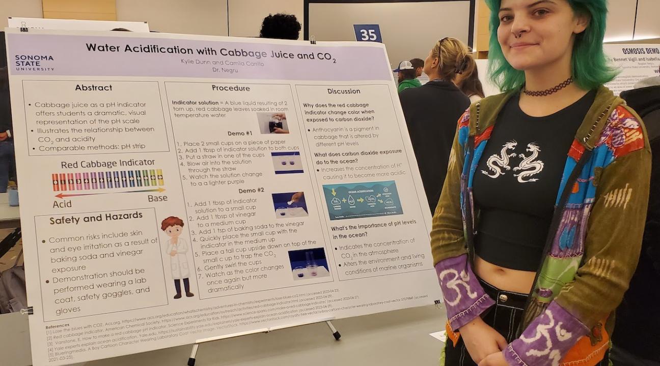 student stands next to her poster