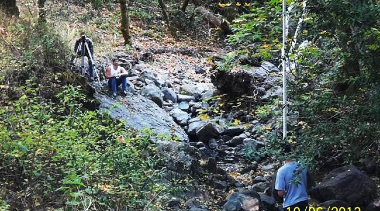 Two people taking measurements of a dry creek bed