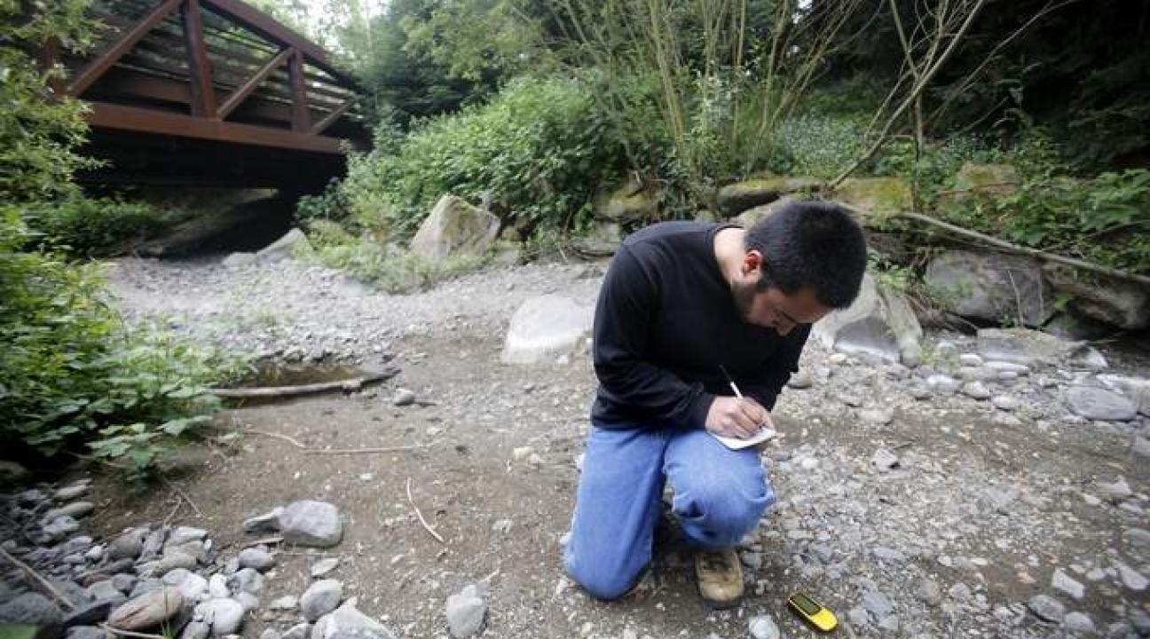 Student uses a GPS device to find a location for a sediment trap