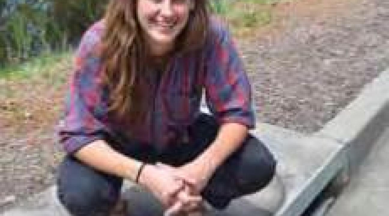 Student squatting over sewer drain