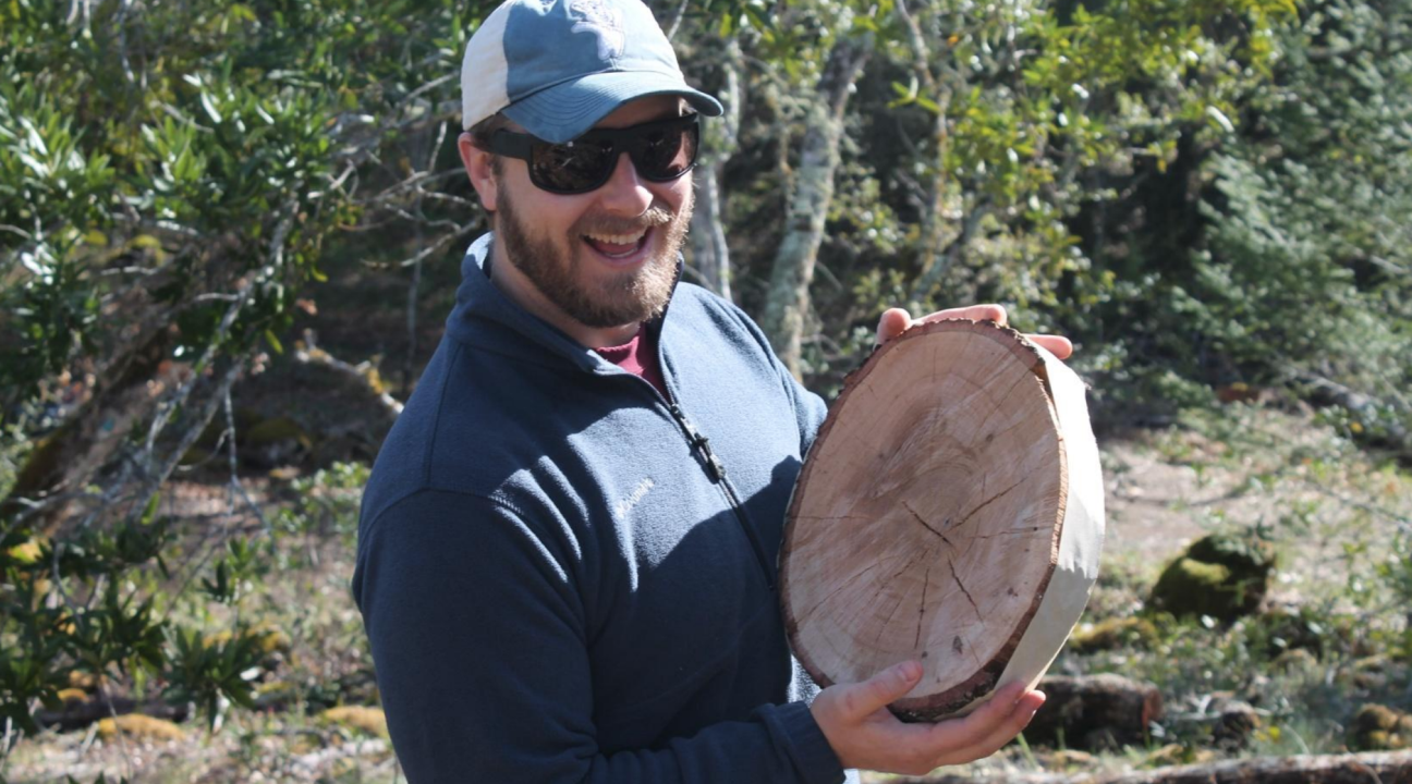 Student holding cross section of a tree trunk