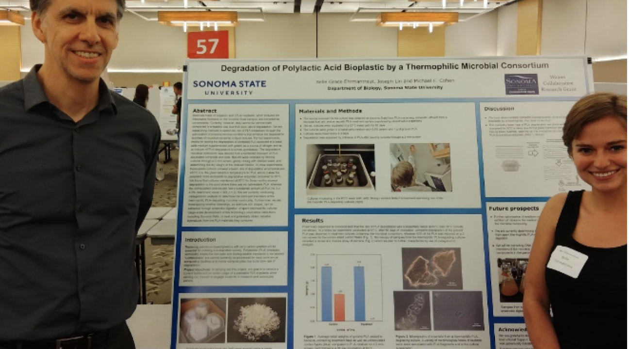 two people stand next to scientific poster