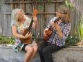 two women play ukuleles outside