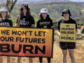 teenagers stand with signs in English and Spanish about wildfire