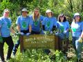 volunteers stand behind a sign for the butterfly garden