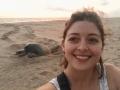 Una investigadora se encuentra en una playa frente a una tortuga marina