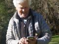 a birder looks at her smartphone in front of trees