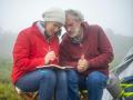 a man and woman sit in nature writing in a notebook