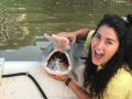 a student holds a paddlefish on a boat and opens her mouth like it does