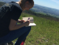 Student sitting in grassy field writing in notebook