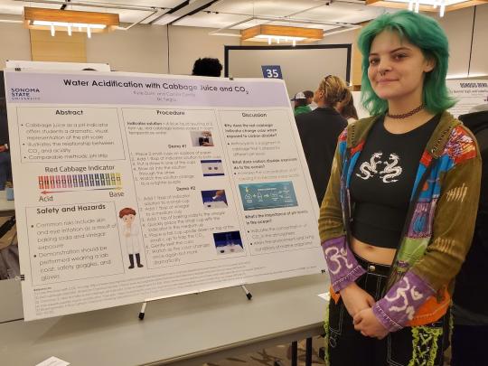 student stands next to her poster