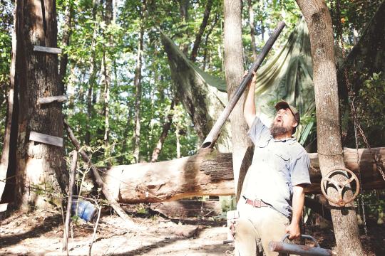 a man holds a stick in the air in the forest