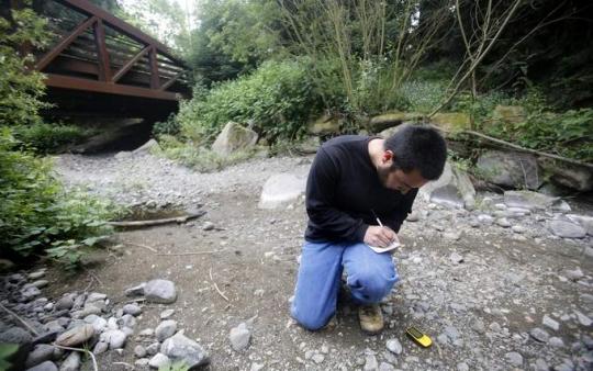 Student taking measurements in a dry creek bed