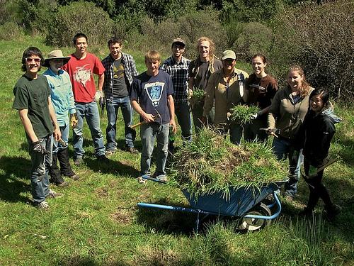 Students and wheelbarrow filled with removed weeds