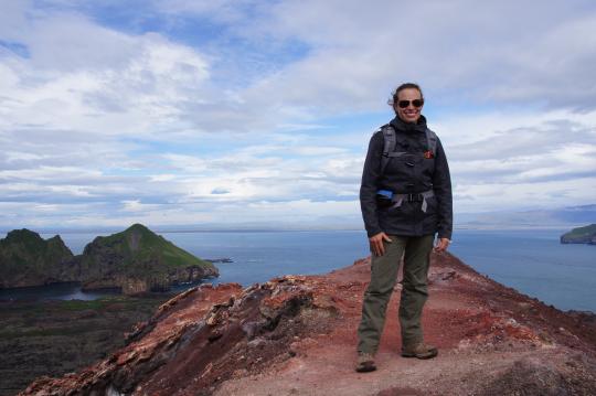 A researcher stands atop a mountain in front of the sea
