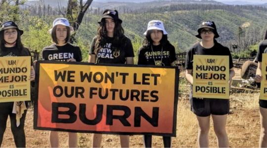 teenagers stand with signs in English and Spanish about wildfire