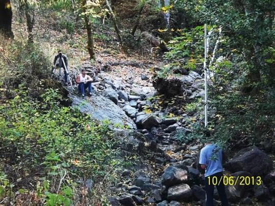 Two people taking measurements of a dry creek bed