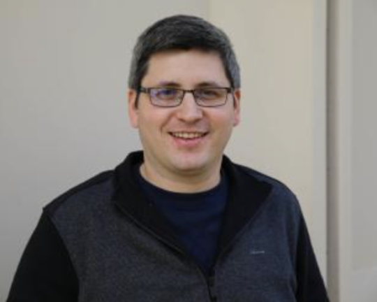 a man with glasses smiles