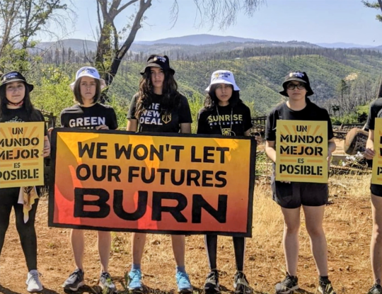 students hold signs reading "we won't let our futures burn" and "un mundo mejor es posible"
