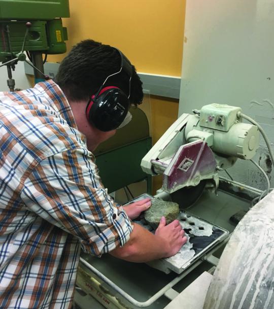 Student making a thin section from a sample of rock