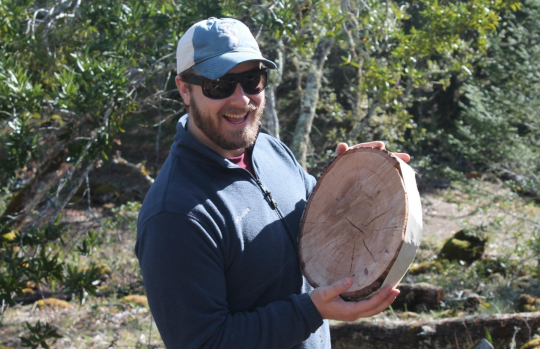 Student holding cross section of a tree trunk