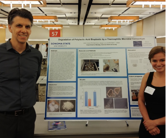 two people stand next to scientific poster