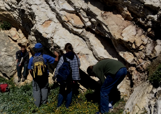 students in front of a rocky wall outside