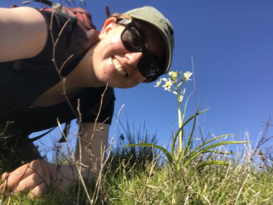 a naturalist poses next to a soap plant in bloom