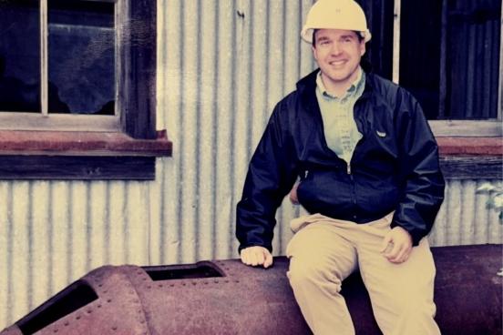 man in hard had sits on huge pipe