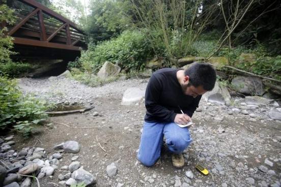 Student taking measurements in a dry creek bed