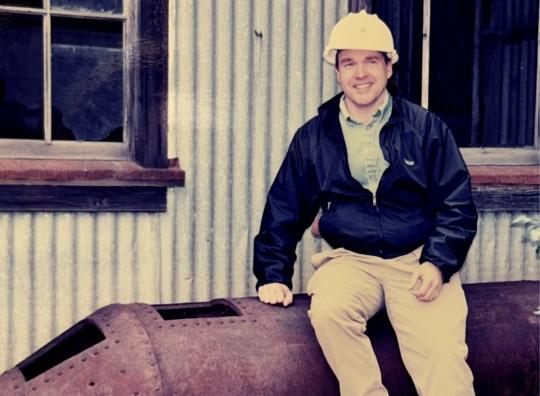 man in hard had sits on huge pipe